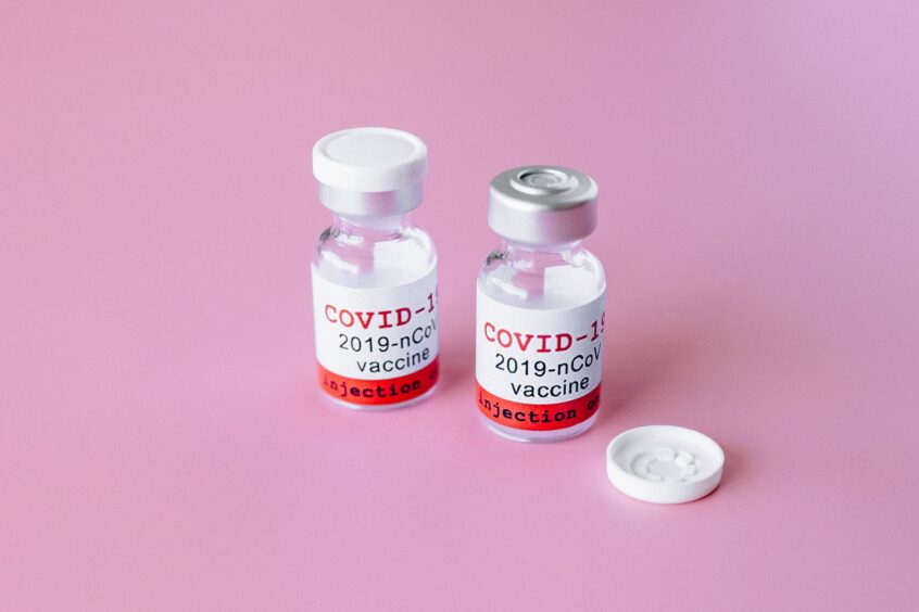 two covid vials on pink surface